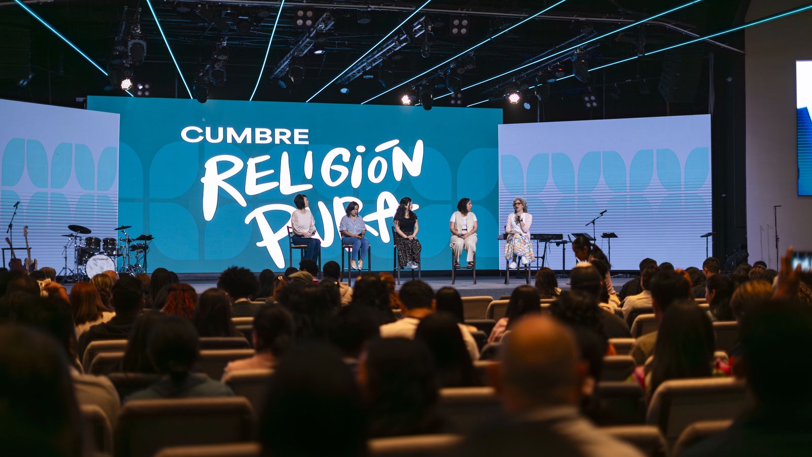 Cinco mujeres conversan en el escenario de la Cumbre Religión Pura frente al público.